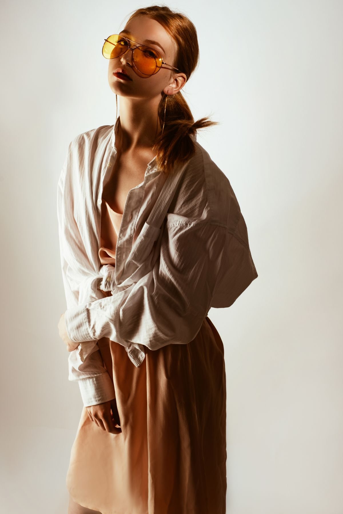 Model in a beige linen shirt and tan trousers against a sunlit wall